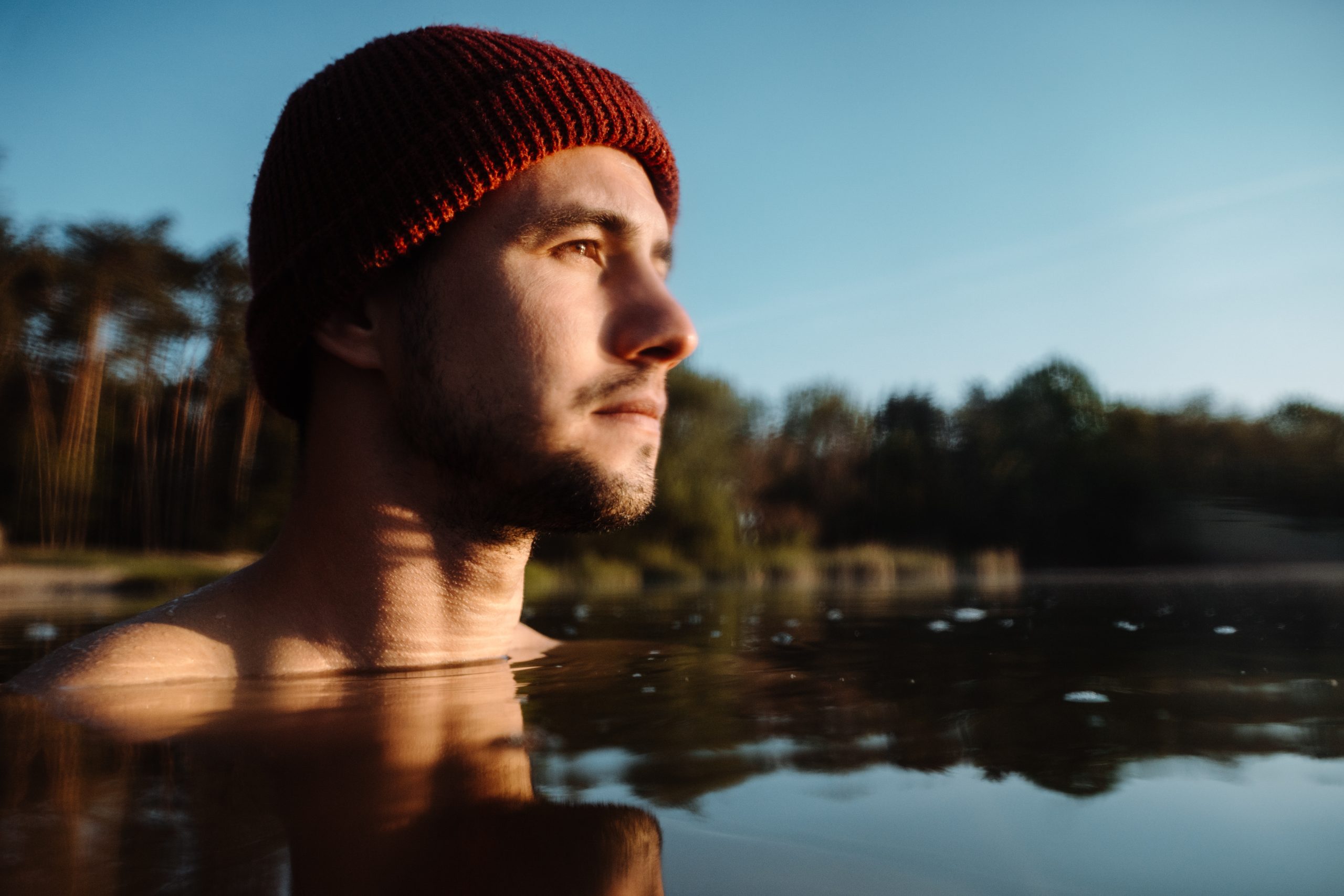 young-man-in-hat-bathing-in-the-ice-water-alone-at-the-morning